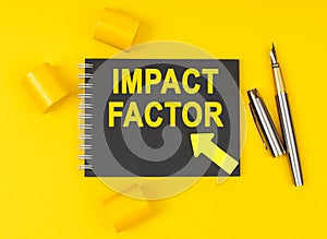 On a yellow background lies a pen, a black notebook with the inscription - IMPACT FACTOR