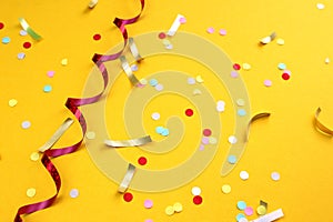 On a yellow background lies a swirling ribbon and festive confetti