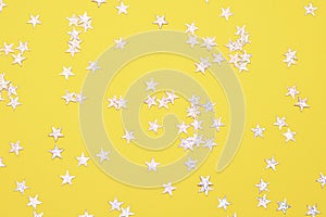 Yellow background with stars, glitter spangles. Christmas concept.