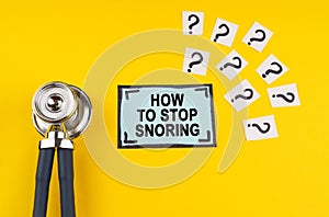 On a yellow background, a stethoscope, question marks and a sticker with the inscription - How to stop snoring