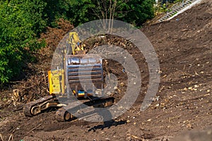 Yellow backhoe with hydraulic piston arm against clear blue sky