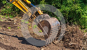 Yellow backhoe with hydraulic piston arm. Heavy machine for excavation in construction site.