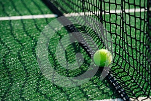 Yellow ball lying on the lower part of the net on a green tennis court