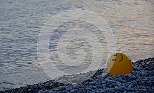 A yellow ball on a pebble beach at sunset