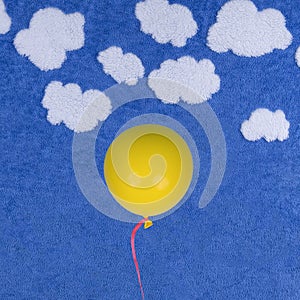 Yellow balloon on blue background with clouds.