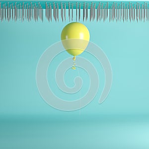 Yellow balloon floating near nail traps on ceiling on blue pastel background