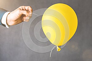 yellow balloon. Man hold needle directed to air balloon.