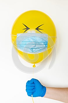 Yellow balloon with medical mask and doodle eyes. Conceptual image of Birthday party during Corona virus quarantine