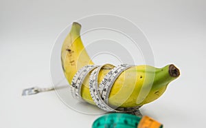 Yellow banana and Measuring tape wrapped around on white background