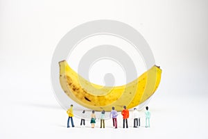 Yellow Banana and miniature models on White Background. Healthy lifestyle, fruit concept. Shallow depth of field, soft focus