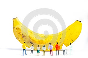 Yellow Banana and miniature models on White Background. Healthy lifestyle, fruit concept. Shallow depth of field, soft focus