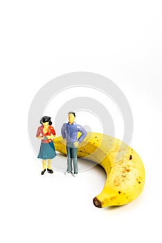 Yellow Banana and miniature models on White Background. Healthy lifestyle, fruit concept. Shallow depth of field, soft focus