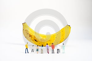 Yellow Banana and miniature models on White Background. Healthy lifestyle, fruit concept. Shallow depth of field, soft focus