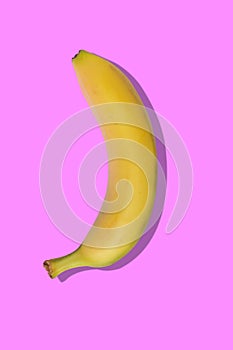 Yellow banana on pink pastel background with a shadow