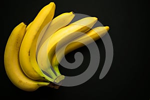 Yellow bananas on a black background. Copy space.
