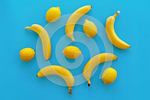 Yellow bananas and lemons on bright blue paper, trendy flat lay.