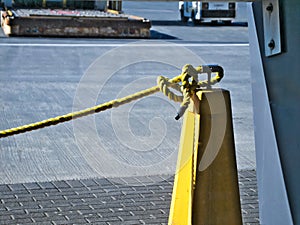 Yellow barrier rope attached to metal post with knot