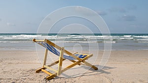 An yellow beach chair rests on the white sand of the beach and B