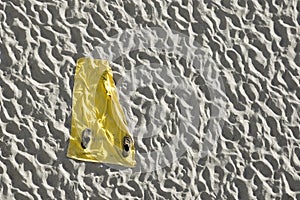 Yellow beach towel on white sand.