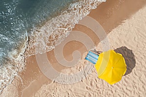Yellow beach umbrella and sunbed on sandy coast near sea, aerial view. Space for text
