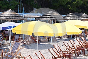 Yellow beach umbrellas and chaise for relax and comfort on sea coast. Happy summer vacations and tourism concept. Paid service on