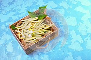 Yellow bean, farm fresh vegetables and organic produce in a wooden box - fresh beans on blue background. top view copy space