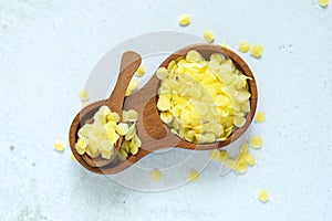 Yellow beeswax pellets in wooden plate