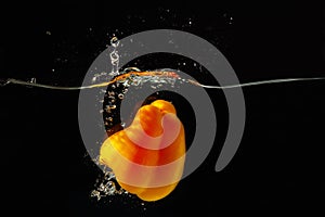 Yellow bellpepper falling into water with splash