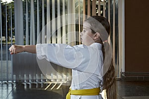 With a yellow belt, a beautiful athlete trains a punch