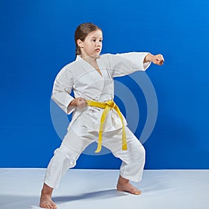 With a yellow belt the girl beats a blow with her hand