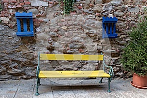 Yellow bench and blue crates on a stone wall in Tuscany