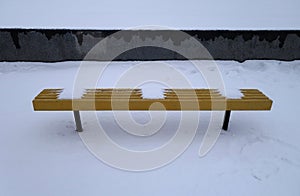 Yellow bench covered with snow