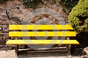Yellow bench in front of stone wall
