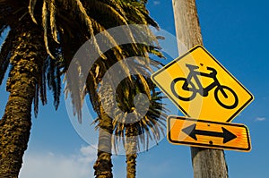 Yellow Bicycle Path Sign with an arrow in a park.