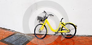 The yellow bicycle for rent park or lean on the white concrete wall