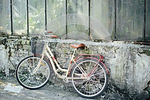 Yellow bicycle is standing in garden, against background of an old brick building. Ð¡oncept of loss, loneliness.