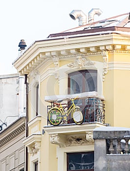 Yellow bicycle suspended on a balcony of an old building