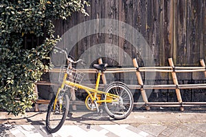 Yellow bicycle on vintage wooden house wall