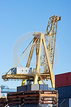 Yellow big crane operates in a warehouse at the seaport