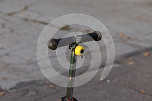 Yellow bike bell on the handlebars of the scooter