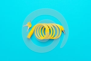 Yellow bike lock with keys over turquoise blue background