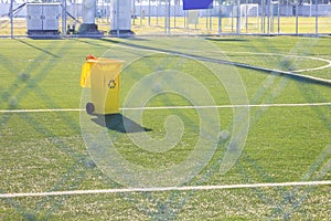 Yellow bin on artificial grass in soccer stadium