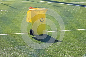 Yellow bin on artificial grass in soccer stadium