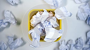 Yellow bin full of crumpled paper, waste material pollution, recycling concept photo
