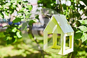 Yellow bird house hanging from the tree and surrounded by lush foliage