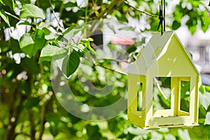 Yellow bird house hanging from the tree and surrounded by lush foliage