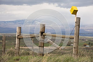 Yellow Birdhouse On A Fence With Mountain Scene In Background