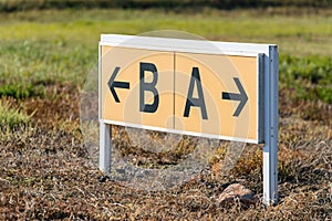 Yellow and black airport direction signs pointing taxiways.