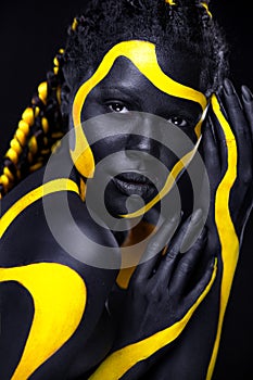 Yellow and black body paint. Woman with face art. Young girl with bodypaint. An amazing model with makeup.