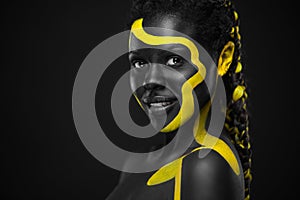 Yellow and black body paint. Woman with face art. Young girl with colorful bodypaint. An amazing afro american model photo
